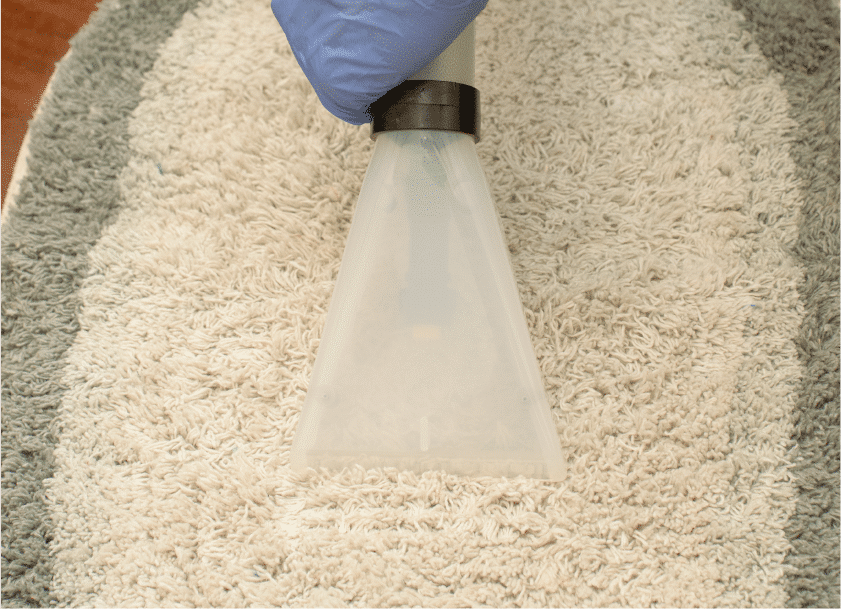 Aspirador sendo aplicado sobre um pequeno tapete felpudo branco co cinza. Imagem ilustrativa texto lavar sofá em Ininga.