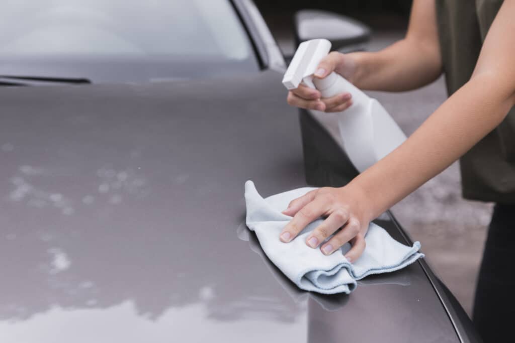 photo of a woman cleaning the car body with a spray bottle and flannel.  illustrative image of the content: jet wash in osasco