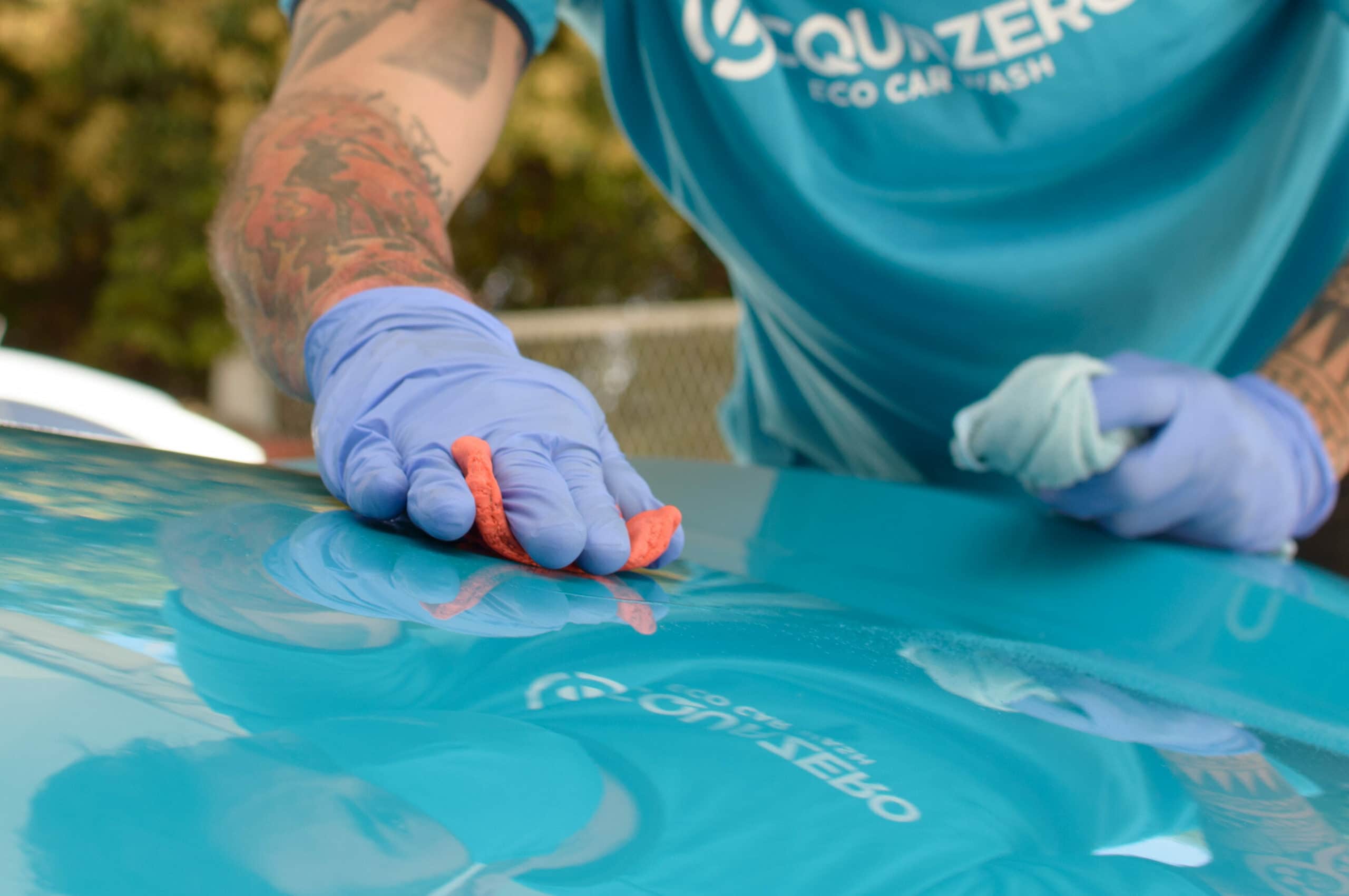 Acquazero employee in the company's uniform, wearing blue gloves and doing a procedure in a blue car, with an orange flannel.  Illustrative image for the text washes jets in natal.