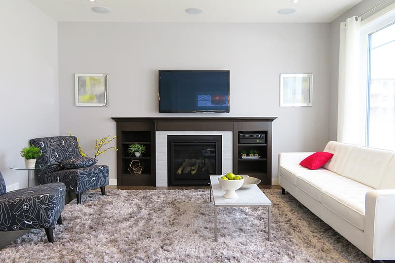 Sala de estar, com lareira, TV de LCD, poltrona e tapete felpudo. Imagem do conteúdo limpar sofá Sabará.