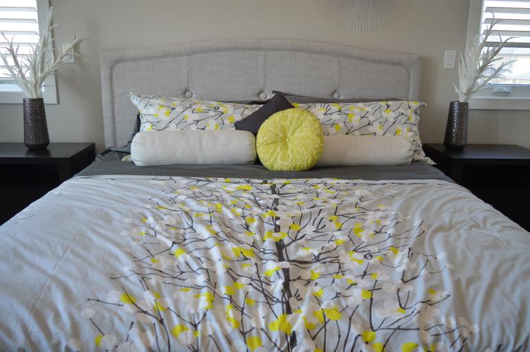 Roupa de cama, travesseiros e almofada com estampa floral. Imagem ilustrativa texto como tirar mau cheiro de colchão. 