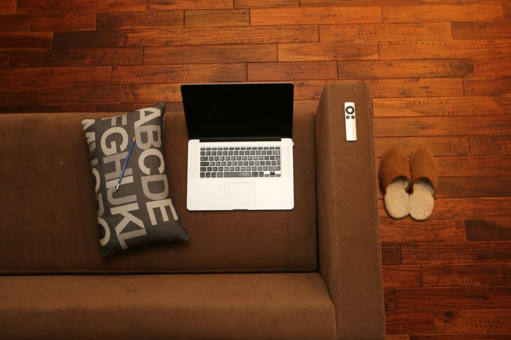O canto de um sofá marrom com um notebook perto da ponta. Imagem de texto sobre impermeabilização de sofá em Águas Claras