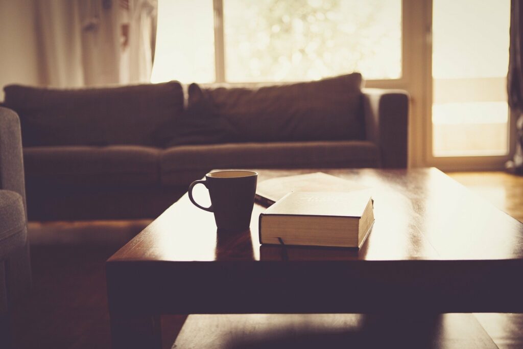 sala de estar com um sofá ao fundo, uma mesa com caneca e livro em cima. imagem ilustrativa texto lavar sofá no paulo afonso