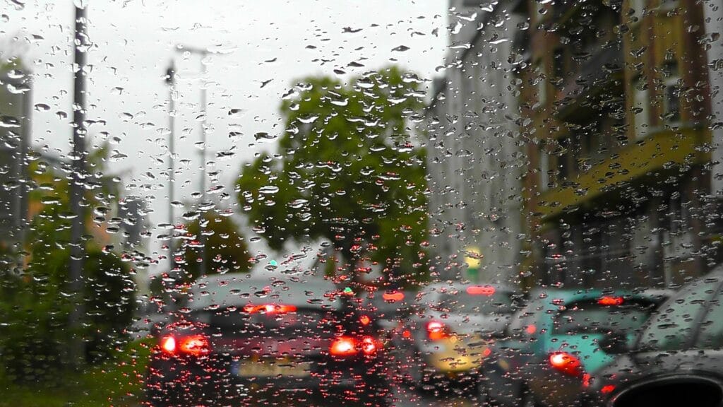 visão de dentro do carro olhando pelo parabrisa molhado e vários carros à frente em um dia chuvoso. imagem ilustrativa texto lava rápido em assis