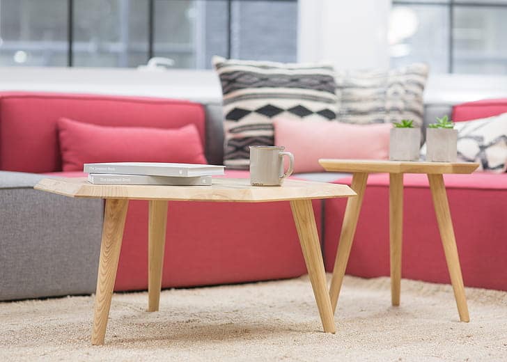 Duas mesas de centro com canecas. Sofá cinza e vermelho, com almofadas. Imagem ilustrativa texto limepza de sofá Bertioga.