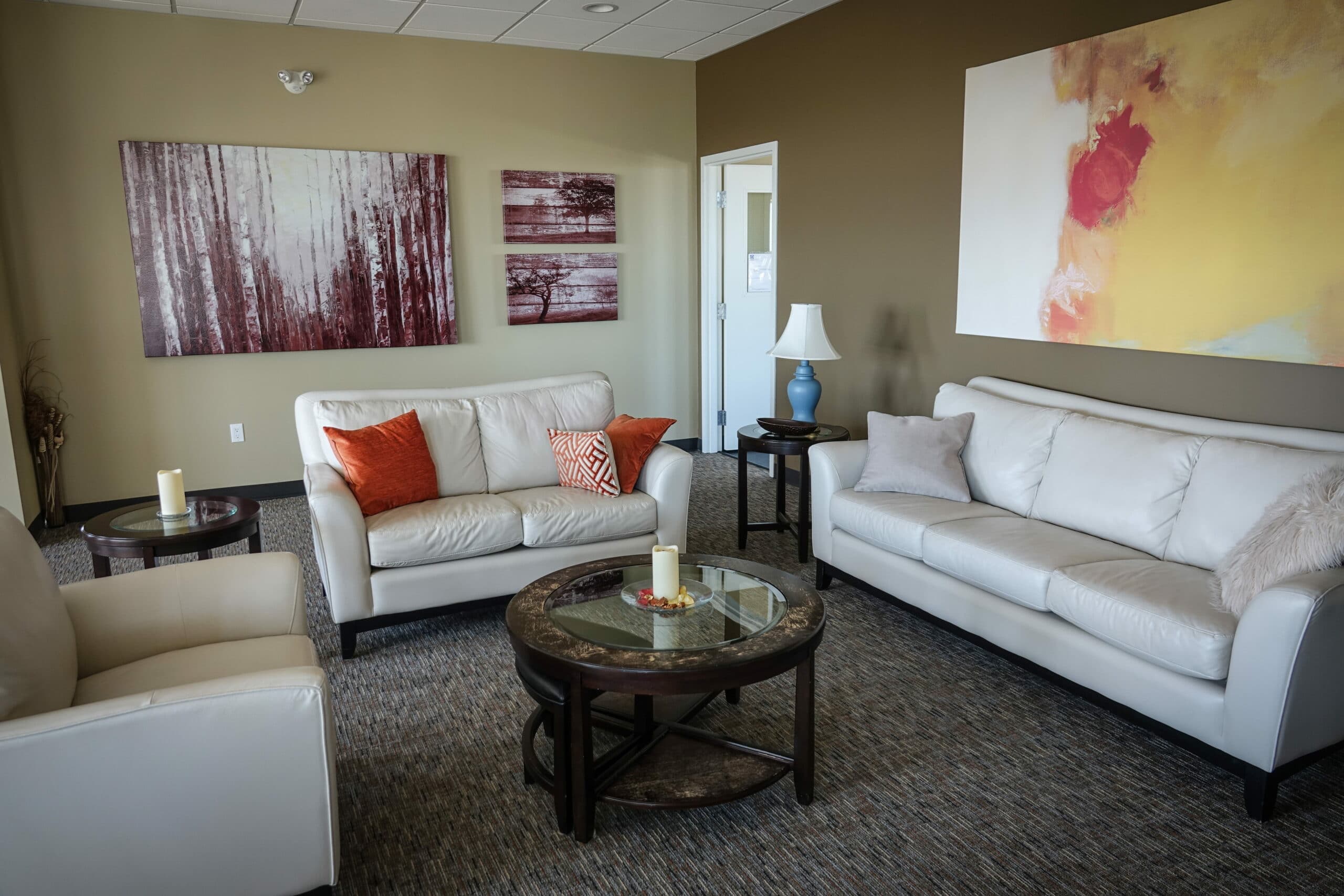 Sala de estar com quadros, tapete cinza, mesa de centro e sofás brancos. Imagem do conteúdo lavar sofá Salvador.
