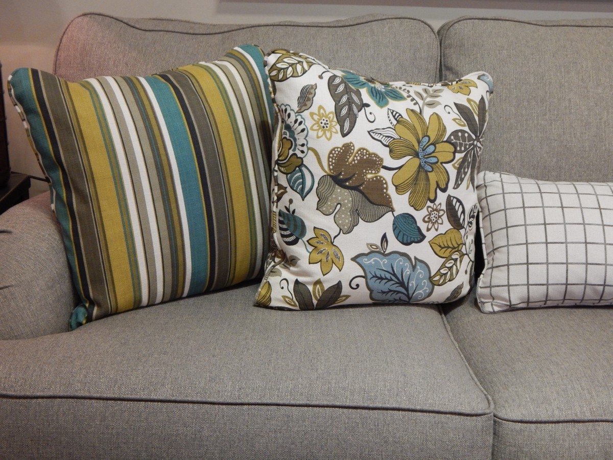 Sofá cinza, com almofafas listrada, floral e xadrez. Imagem ilustrativa texto lavar sofá Nova Parnaíba.