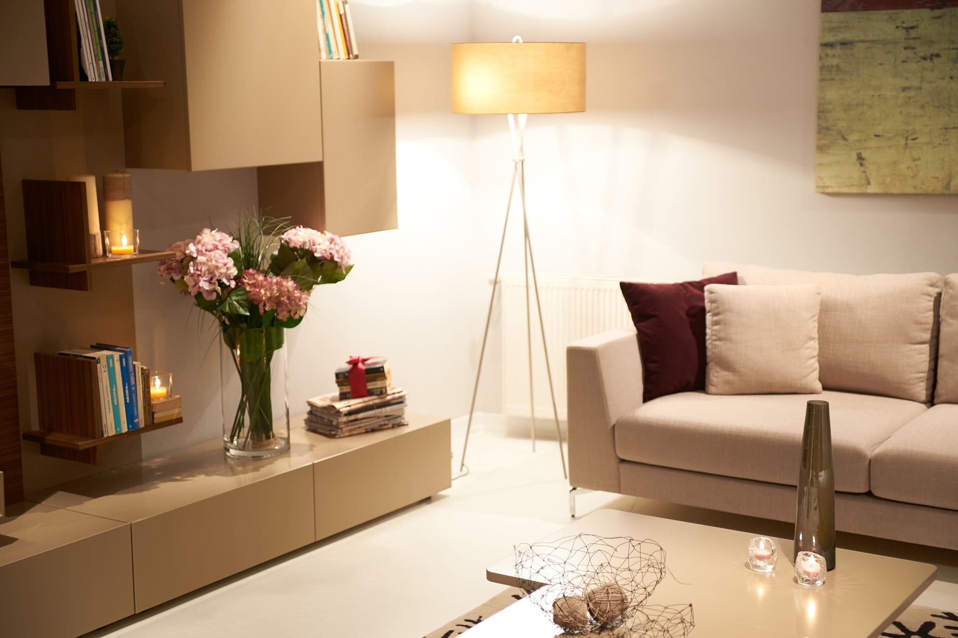 sala de estar com uma luminária no canto, estantes e um sofá branco com almofadas em cima. imagem ilustrativa texto lavar sofá no centro de ponta grossa