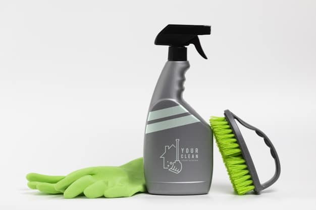 Borrifados cinza com uma escova com cerdas verdes e uma luva verde ao lado. Imagem ilustrativa texto como lavar tapete felpudo.