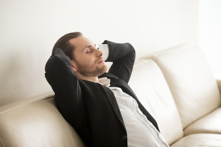 Homem sentado em sofá de couro branco relaxando. Imagem ilustrativa sobre o texto limpar couro branco.