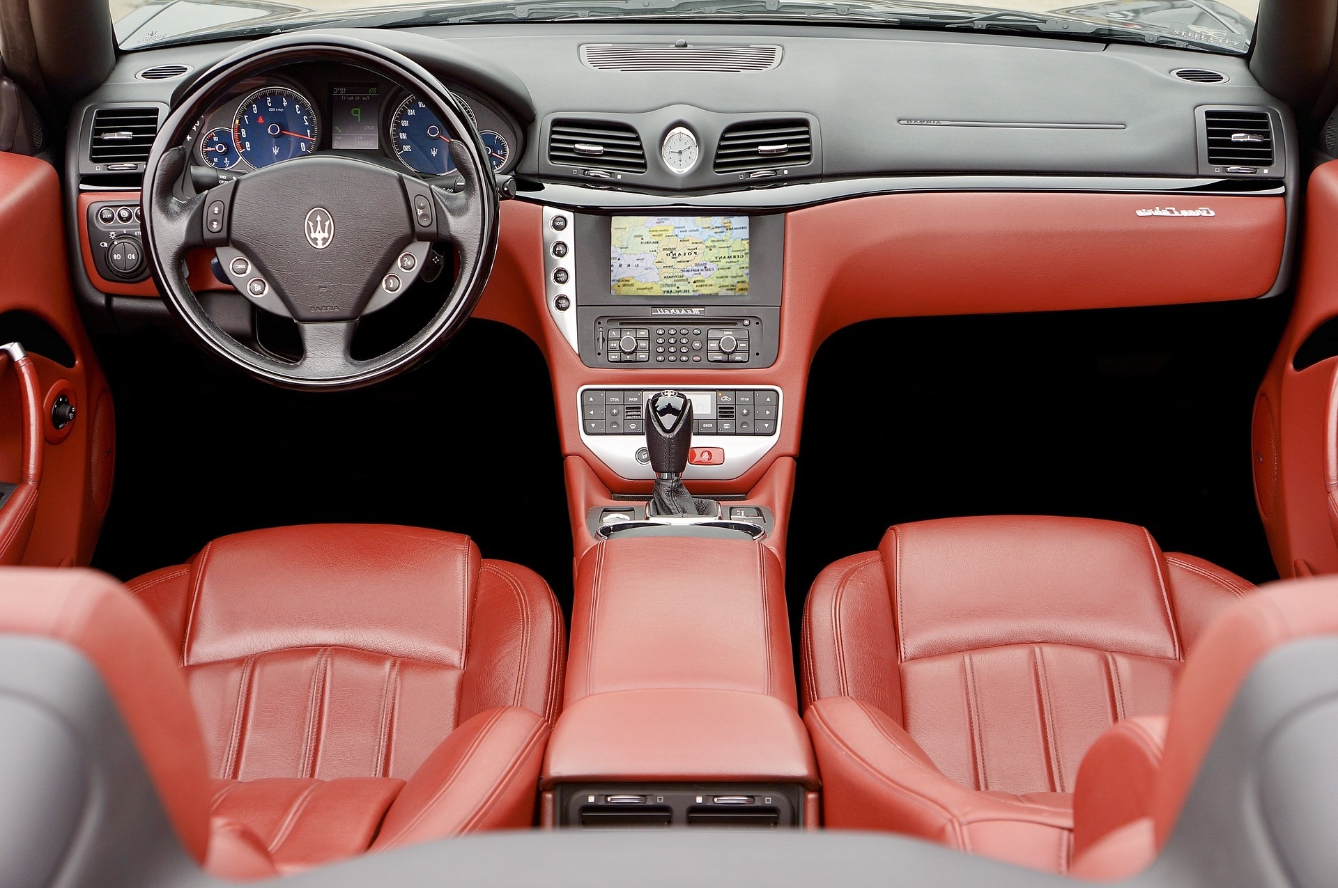 Vista por cima de interior de veículo com bancos de couro vermelhos e GPS. Imagem ilustrativa texto banco de couro automotivo.