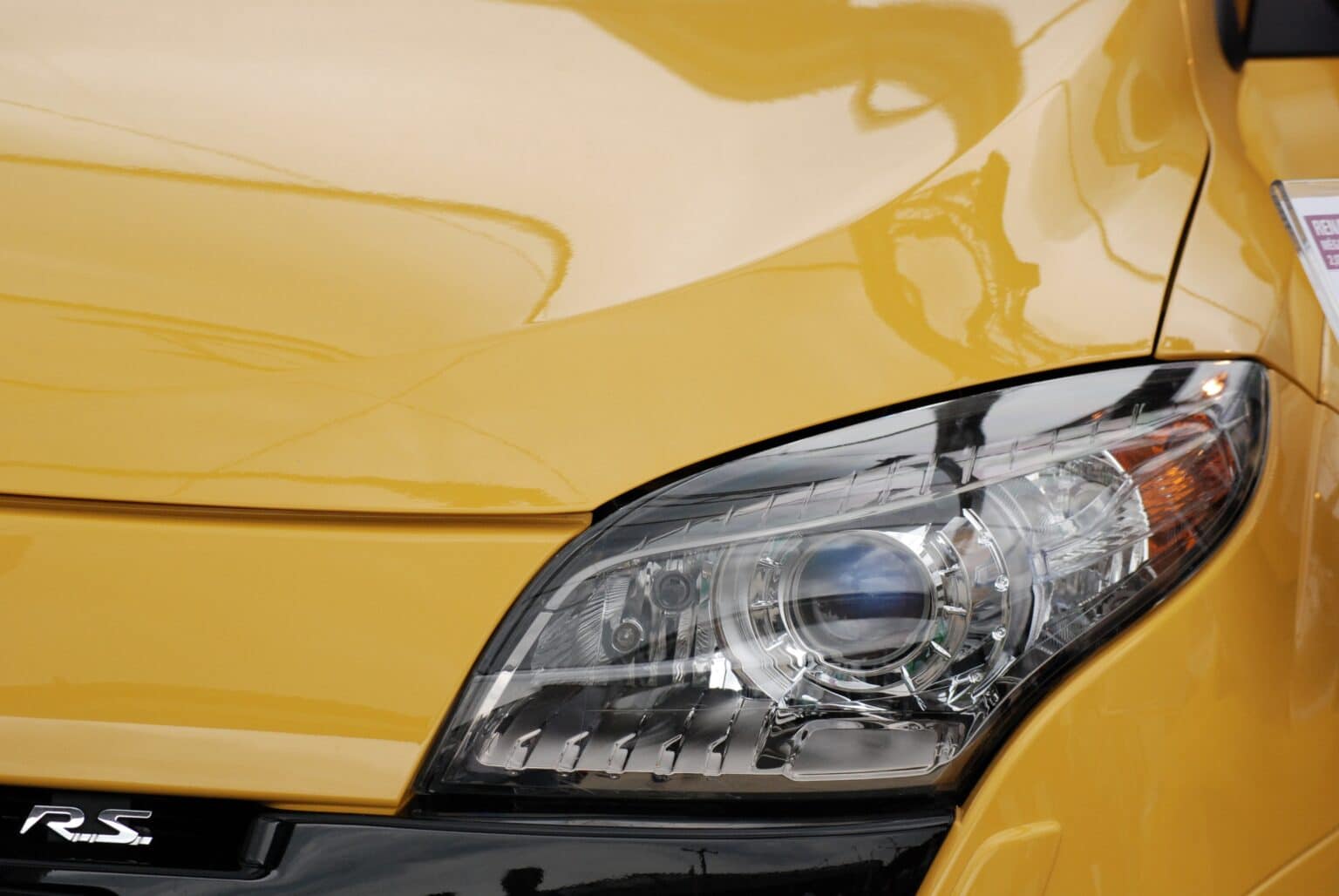 Detalhe de farol dianteiro de carro amarelo. Imagem ilustrativa texto lavar carro Centro Floripa.