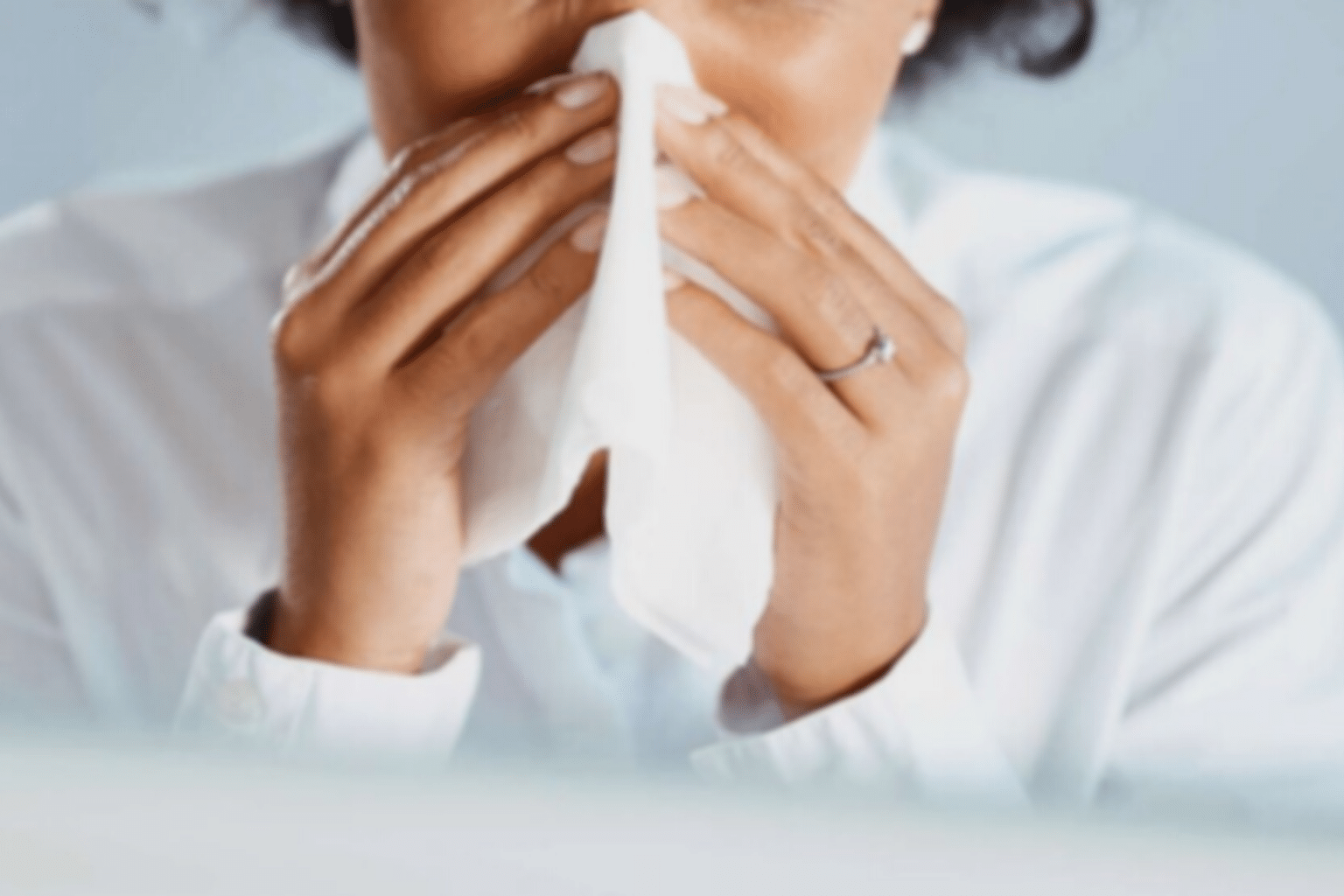 Mulher assoando o nariz com lenço. 