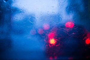 Trãnsito na chuva, visto pelo para-brisa molhado. Imagem ilustrativa texto mancha de vidro automotivo.