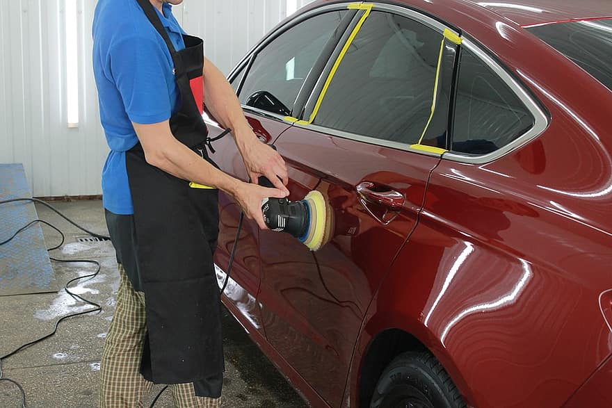 Pessoa encera um carro vermelho com o auxílio de um dispositivo elétrico. Ilustração do texto sobre polimento carro Bh.