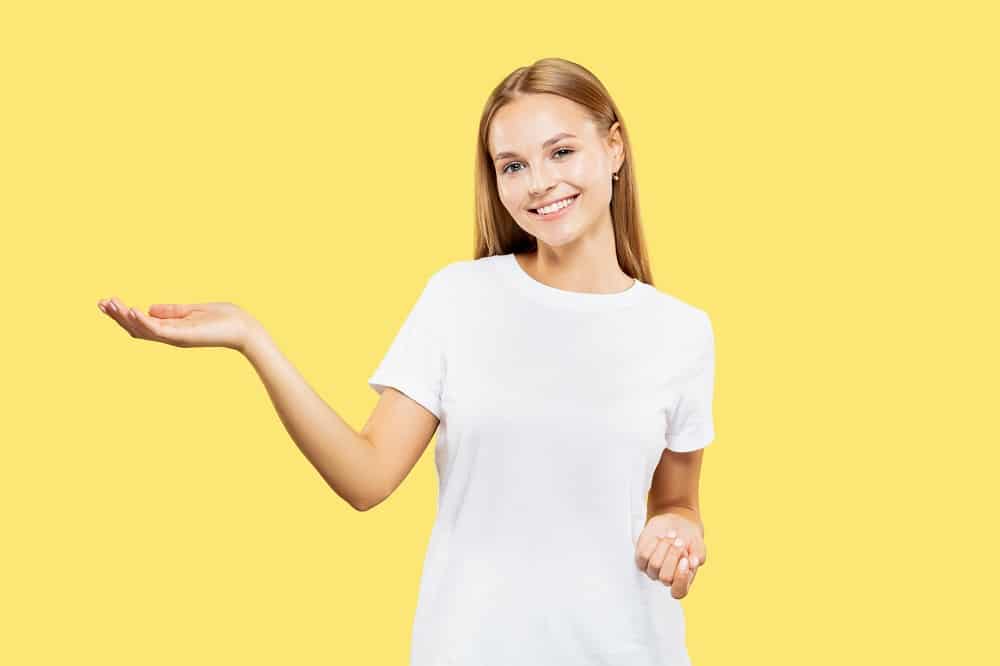 mulher sorridente apontando para o lado em fundo amarelo. Imagem ilustrativa do texto sobre como acabar com mofo