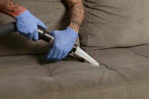 pessoa com luvas azuis limpando sofá. Imagem ilustrativa do texto sobre impermeabilizar sofá