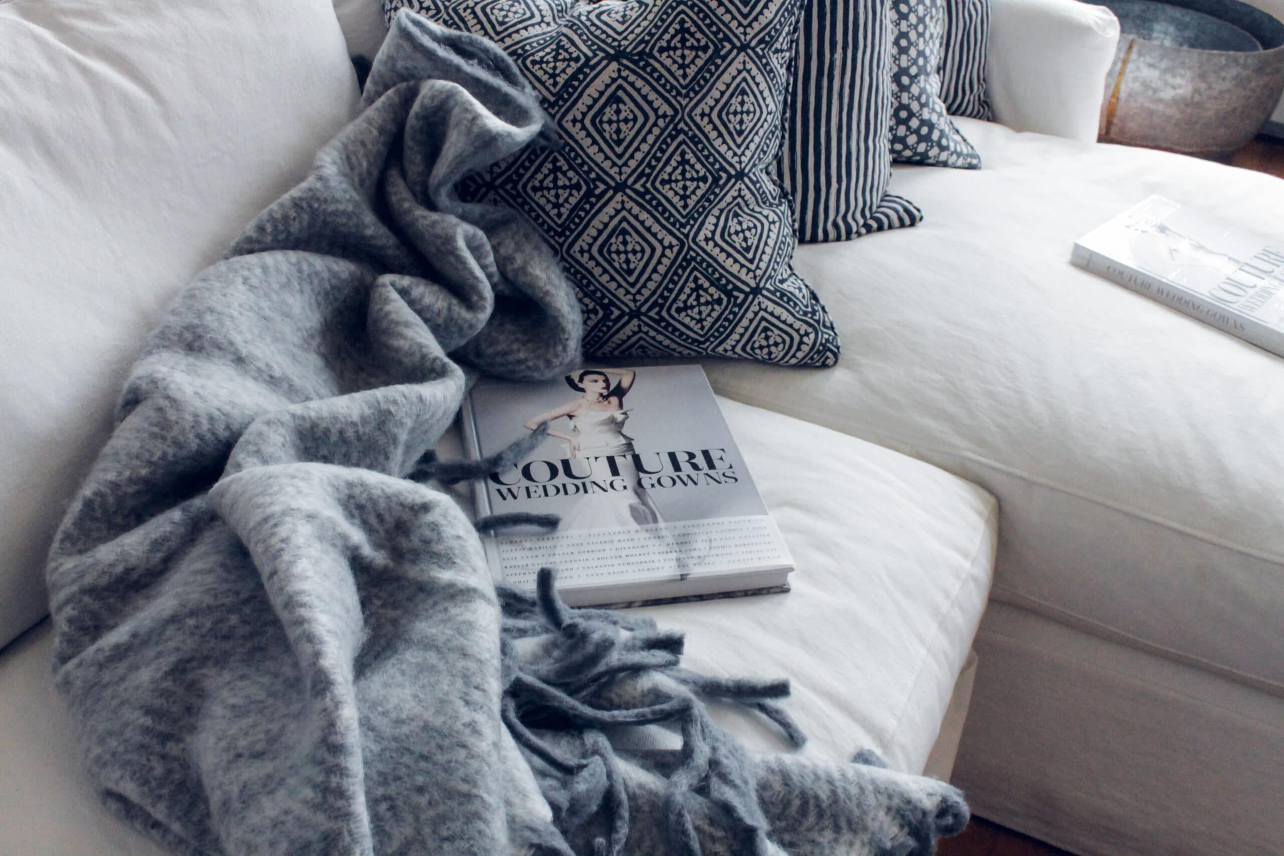 Foto de um sofá branco com coberta e almofadas. Imagem ilustrativa para o texto limpar sofá Crixás.