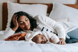 Mulher e bebê deitados em uma cama com edredom branco. Ilustração do texto sobre lavagem de cobertor e edredom.