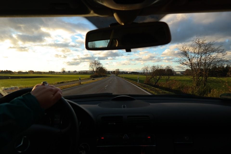 Foto da janela de um carro com pessoa dirigindo. Imagem ilustrativa para o texto como tirar mancha do vidro do carro.
