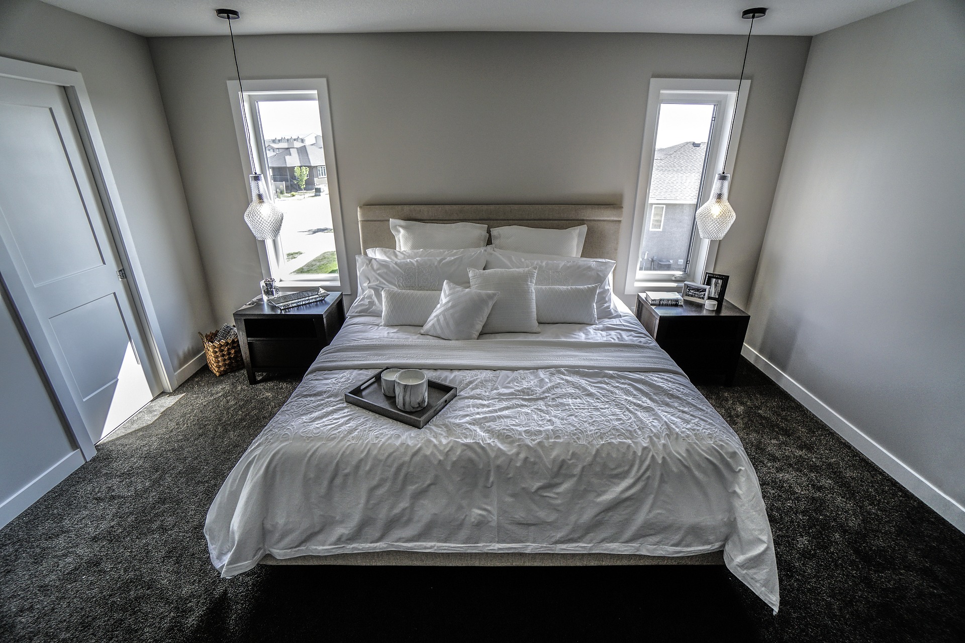 Foto de um quarto com cama branca e carpete cinza. Imagem ilustrativa para o texto manter seus carpetes limpos.