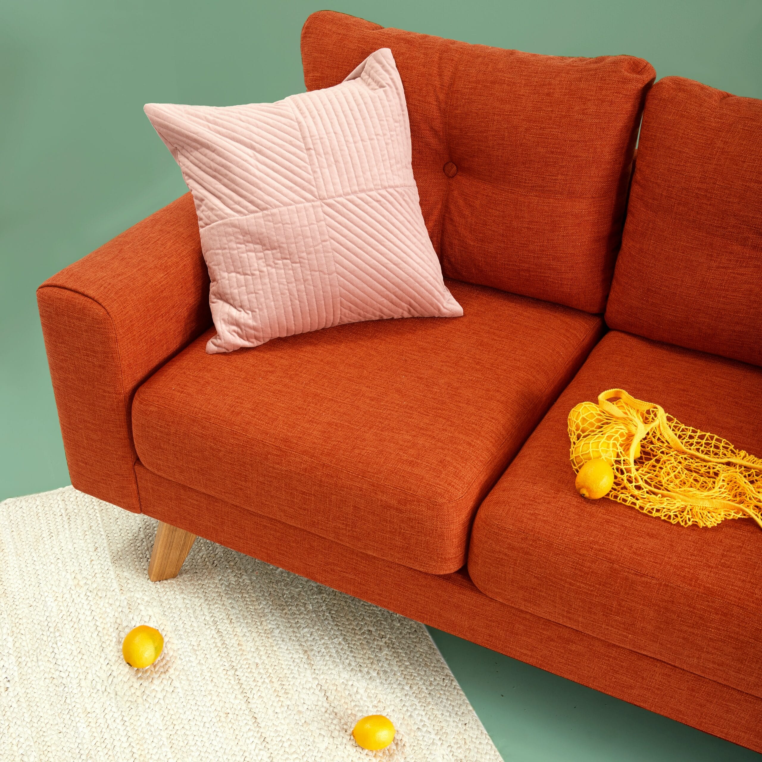 Sofá laranja com almofada rosa em uma sala de estar. Ilustração do texto lavar sofá no Lago Azul, Araçoiaba.