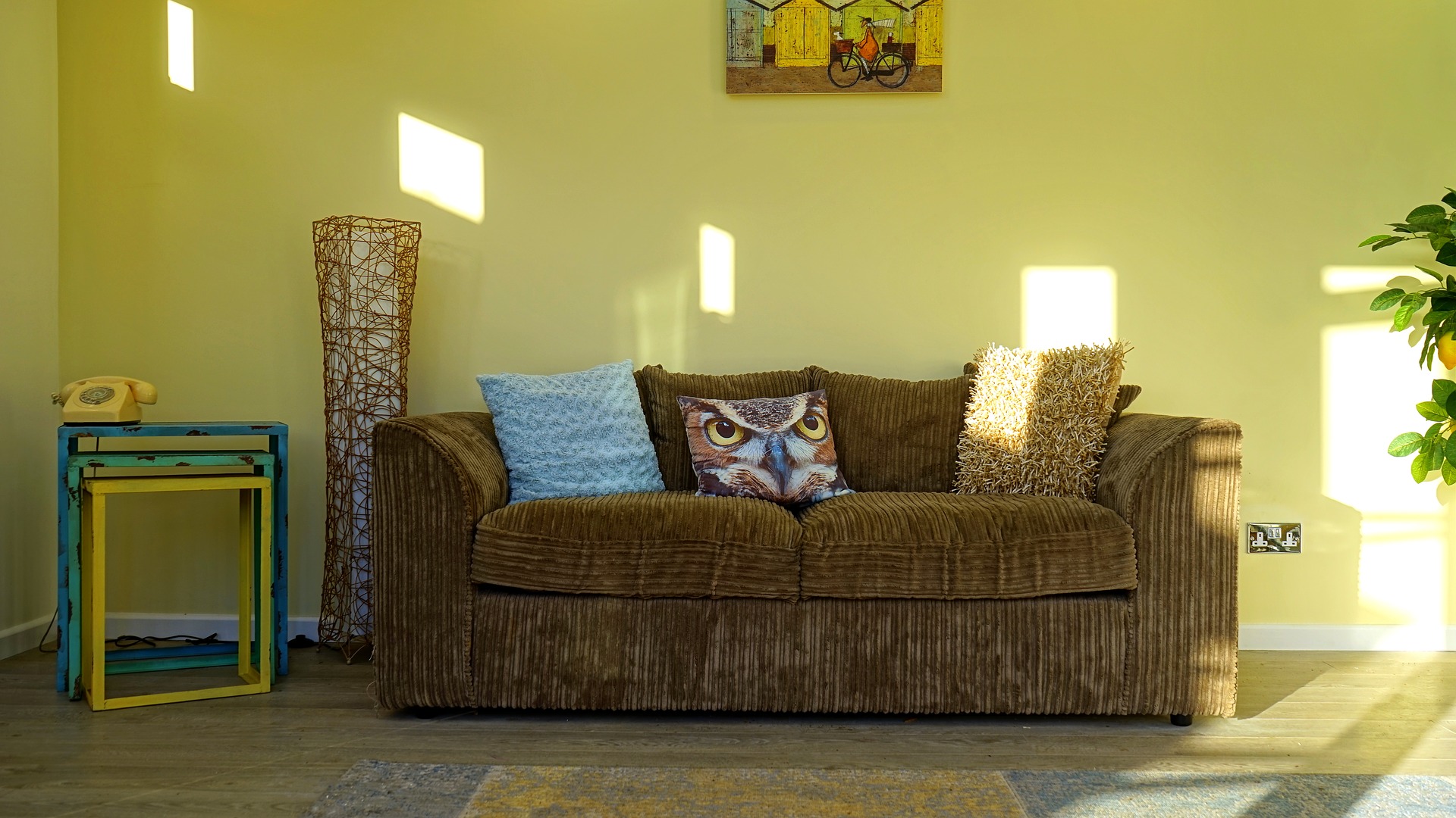 Sala de estar com um sofá marrom e almofada estampada. Ilustração do texto sobre limpar sofá Villas do Atlântico.