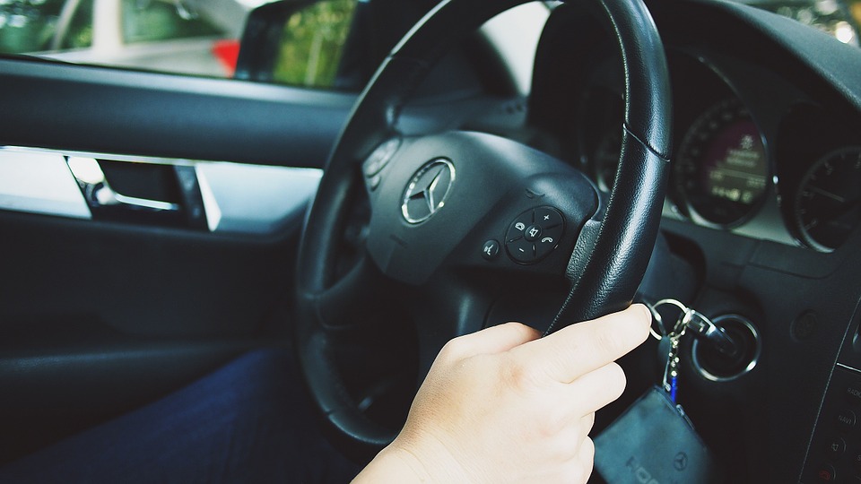 Foto do volante de um carro com pessoa segurando. Imagem ilustrativa para o texto restaurar os plásticos do automóvel.