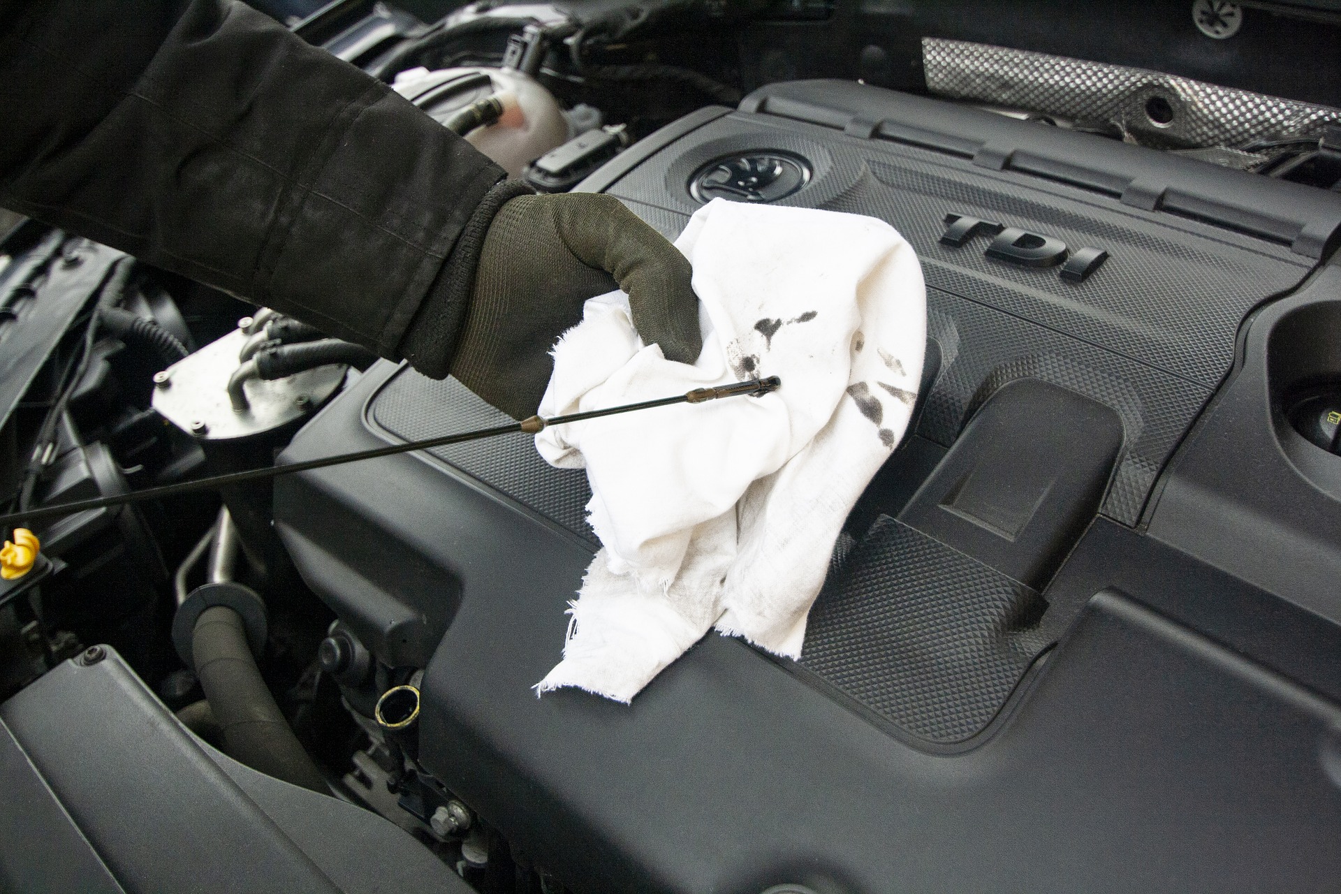 Foto de uma pessoa mexendo no motor de um carro. Imagem ilustrativa para o texto como limpar o motor de carro.