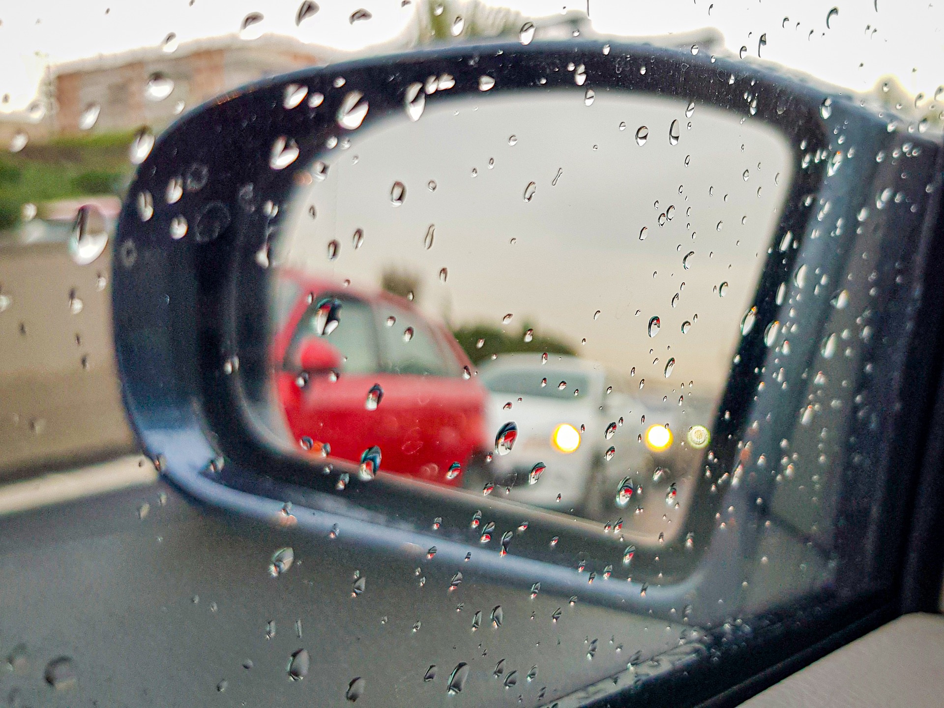 Foto da janela molhada e retrovisor de um carro. Imagem ilustrativa para o texto descontaminação de vidros.