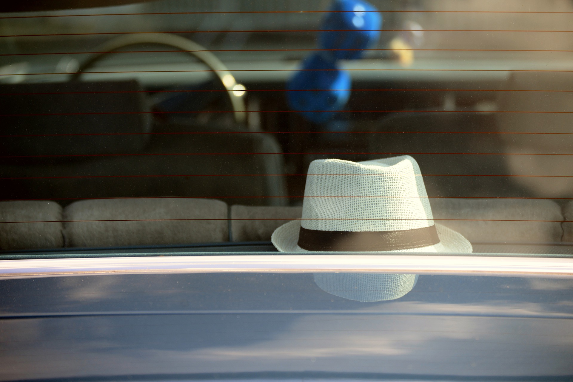 Janela de um carro com um chapéu dentro. Imagem ilustrativa para o texto polimento de vidros.