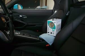Aparelho de oxi-sanitização dentro de um carro com bancos pretos. Ilustração do texto sobre como é feita a oxi-sanitização.
