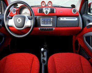 interior de um carro vermelho visto de frente com foco no painél e bancos. Imagem ilustrativa do texto sobre como lavar bancos de carros