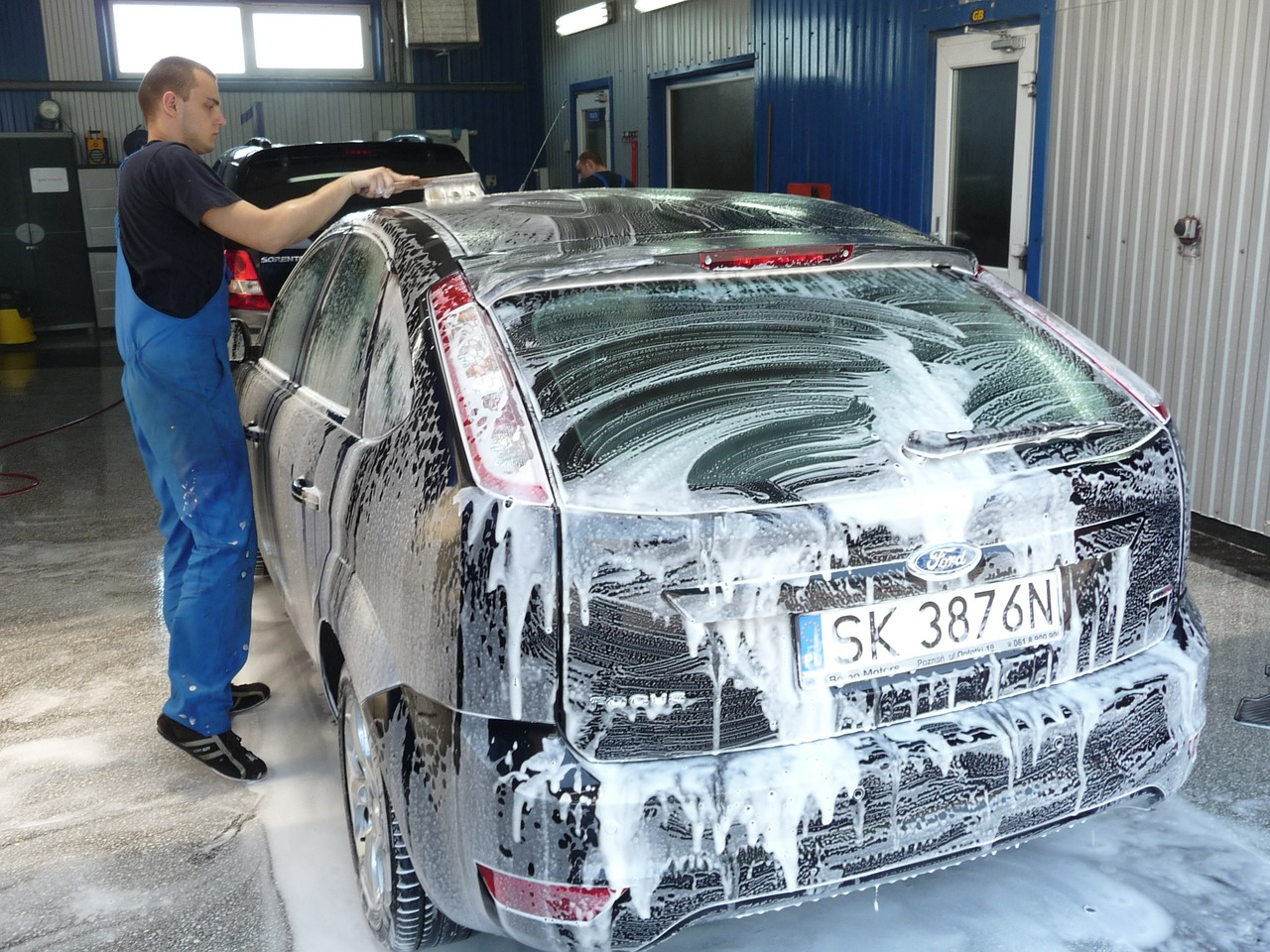Homem limpando carro com espuma. Imagem ilustrativa sobre o texto pré-lavagem automotiva.