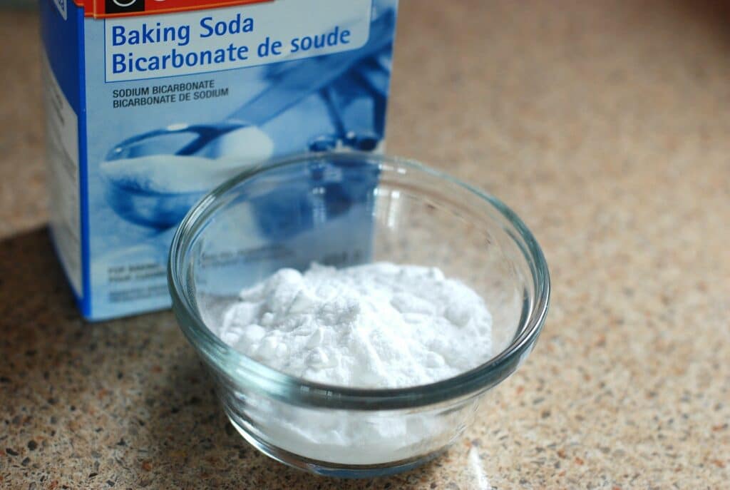 Bicarbonato de sódio em uma vasilha transparente e uma caixa ao lado. Imagem ilustrativa do texto sobre limpar colchão encardido rapidamente.