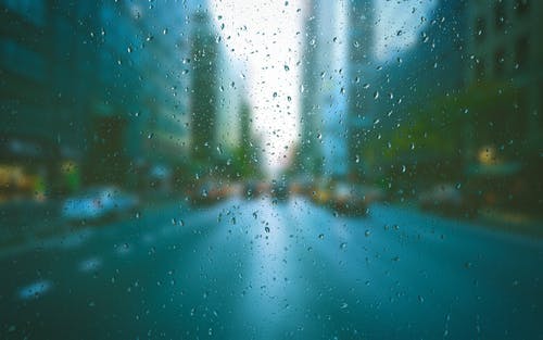 Vidro de carro com gotículas de água da chuva. Imagem ilustrativa do texto sobre polimento de vidro automotivo.