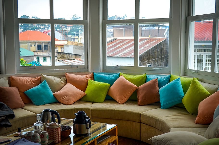 sofá circular com várias almofadas coloridas. Imagem ilustrativa do texto sobre lavagem estofados